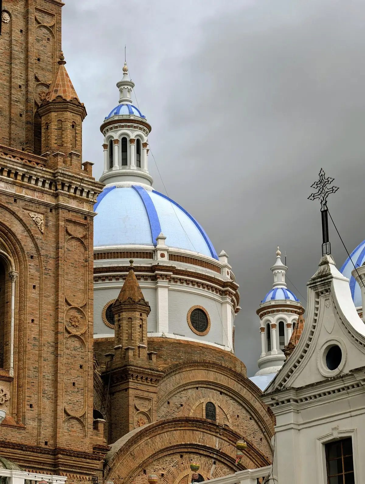 Las cúpulas de azulejo azul de la Catedral Nueva de Cuenca junto a una torre de ladrillo, en un día nublado